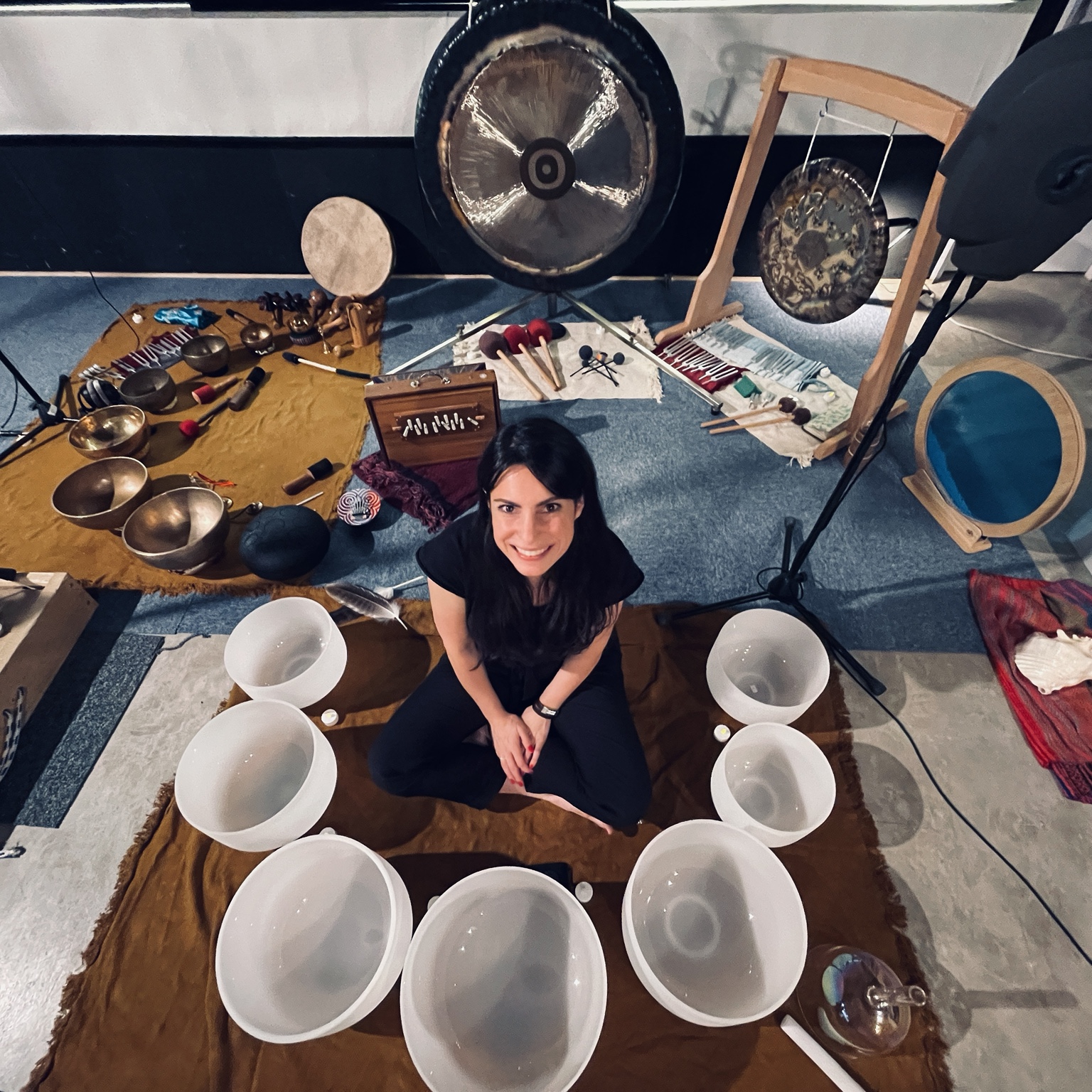 Mélanie Zadeh entourée de bols, de gongs et d’instruments lors d’un enregistrement binaural pour Audible
