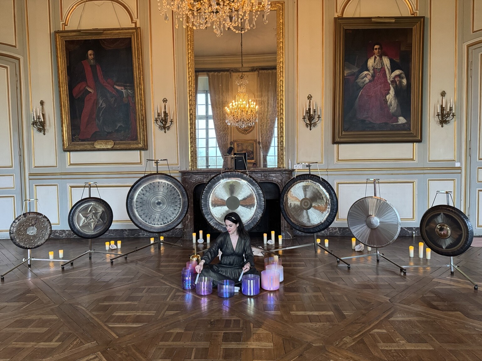 Mélanie Zadeh entourée de gongs et de bols de cristal dans un salon historique