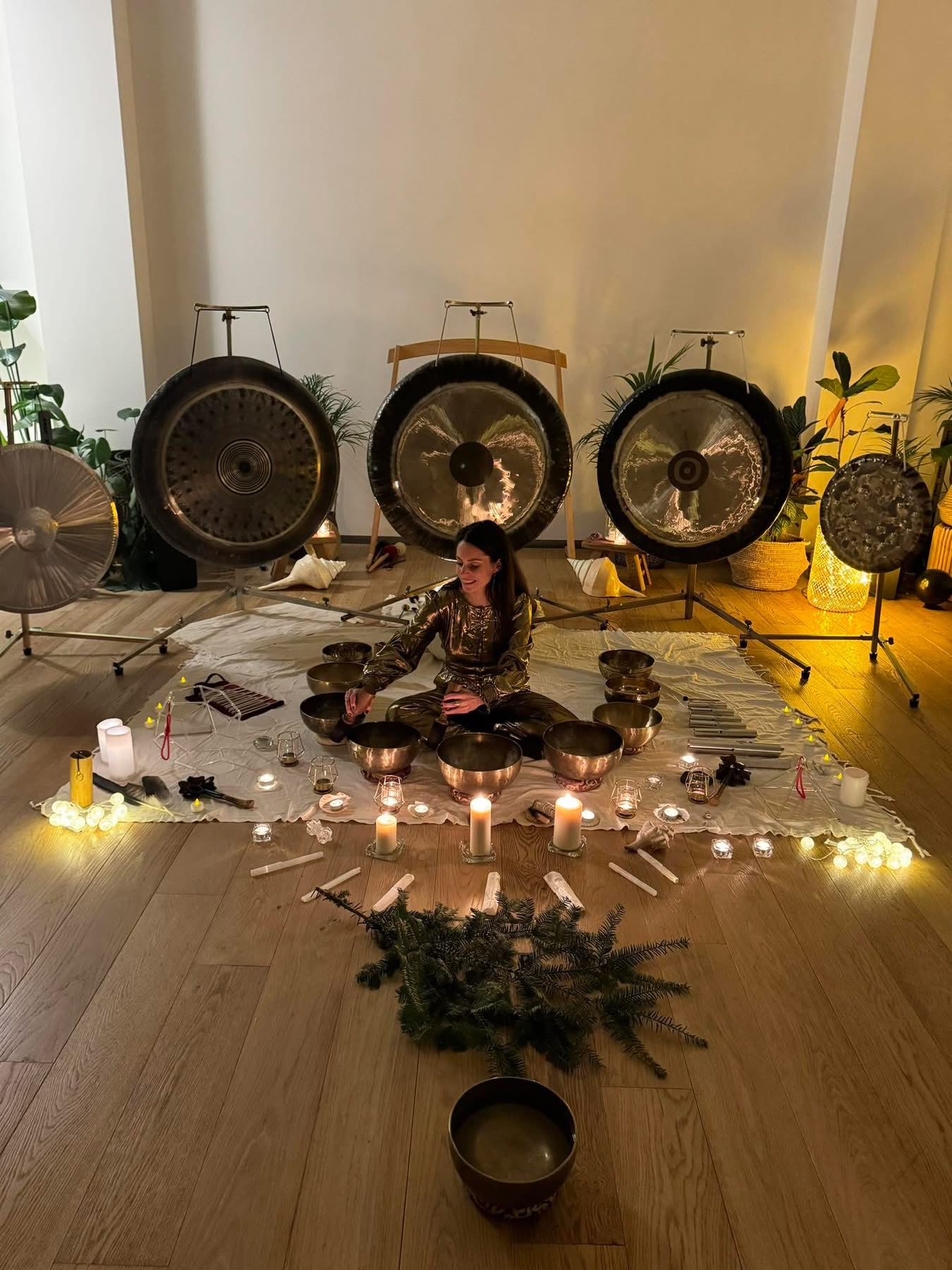 Mélanie Zadeh entourée de gongs, de bols et de bougies lors d’un événement sonore de Noël dans un studio parisien