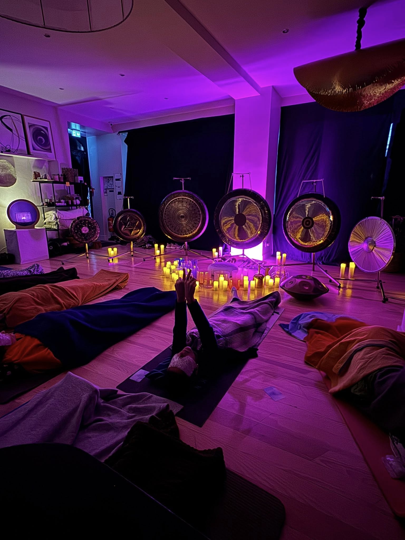 Participants allongés face à une installation de gongs, de bols de cristal et de bougies lors d’une expérience sonore créée en boutique