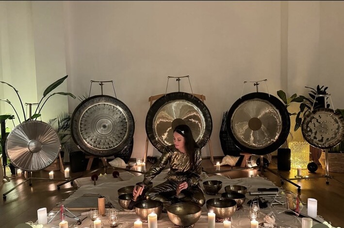 Mélanie Zadeh au centre d’une installation de gongs, de bols tibétains et de bougies à Paris