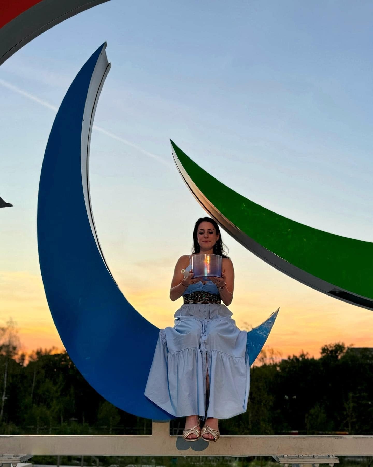 Mélanie Zadeh tenant un bol de cristal devant les Agitos des Jeux Paralympiques de Paris 2024